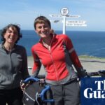 The couple with their bikes in front of a sign